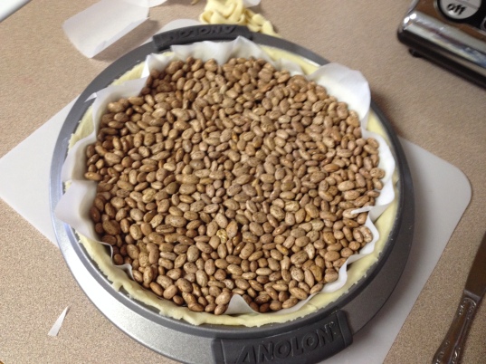 parchment and dried beans placed over crust