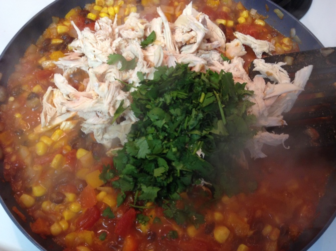 adding shredded chicken and cilantro to vegetable mix for Mexican Chicken Tortilla Pie