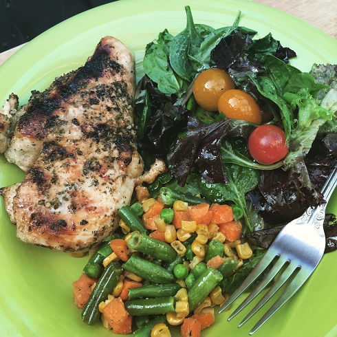 Plated Mediterranean BBQ Chicken and a side of Garlic Lemon Vegetables and a salad