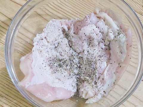adding salt and pepper to chicken breast