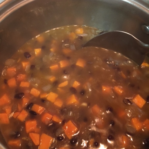 mixing ingredients with chicken broth in a large sauce pot