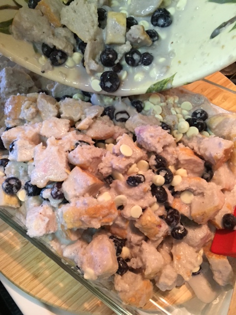 adding Blueberry White Chocolate Bread Pudding to a glass baking dish