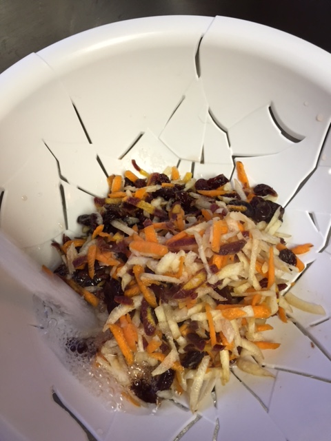 rinsing shredded carrots and dried cherries under running water 